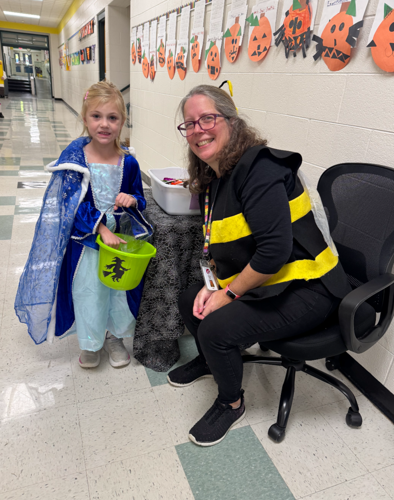 A first grade teacher wearing a bee costume and a student wearing a princess dress.
