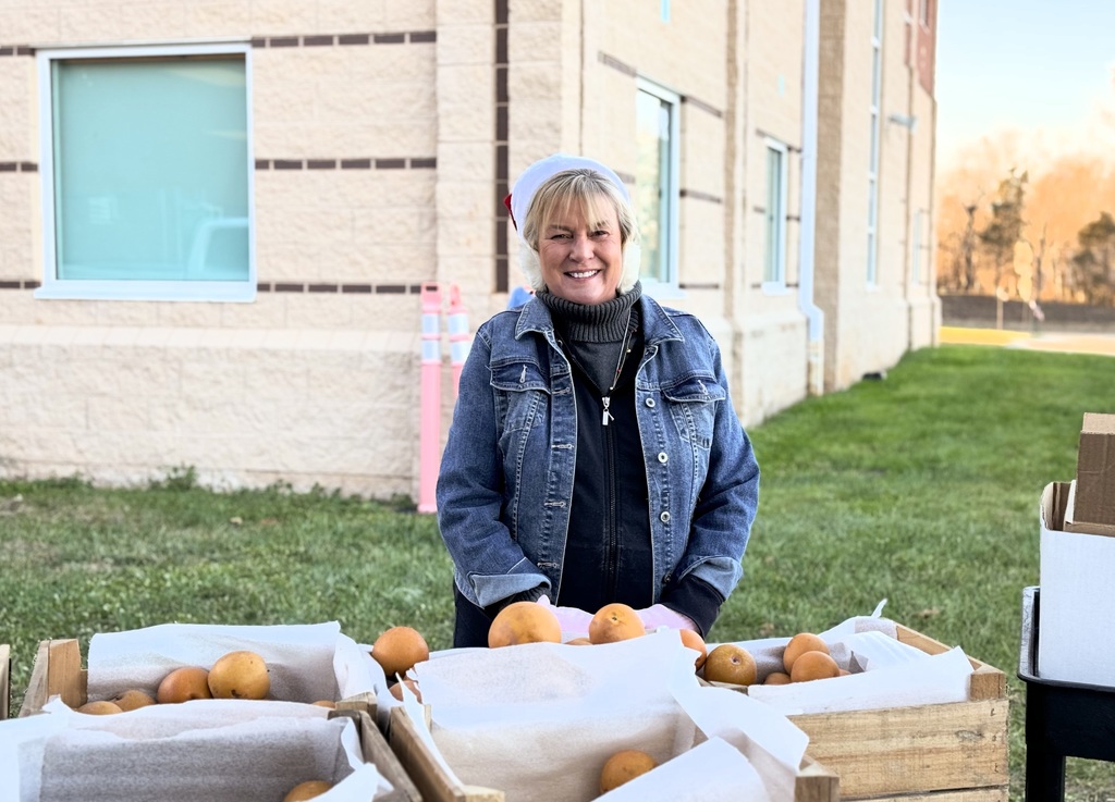 Person standing behind pears smiling