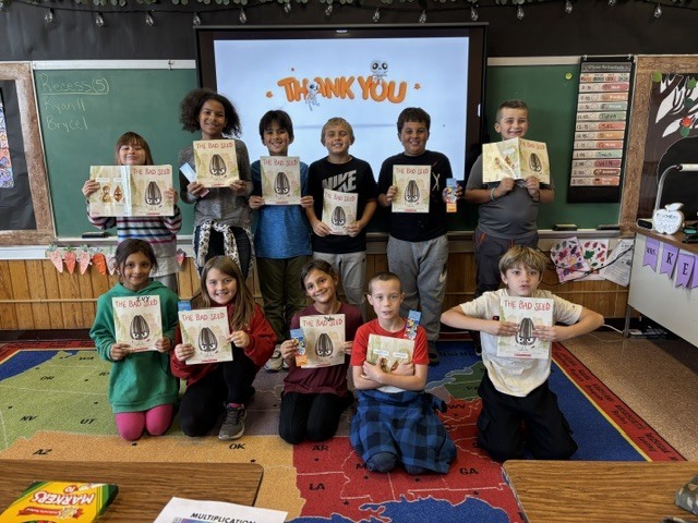 11 - 3rd/4th grade students holding up the book "The Bad Seed" that they received from the "Sponsor a Reader" program