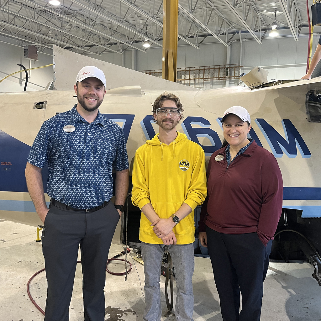 Three people standing in front of an airplane 
