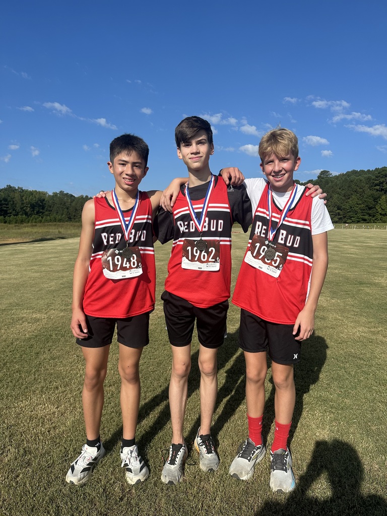 Three boys posing with medals they won from a race.