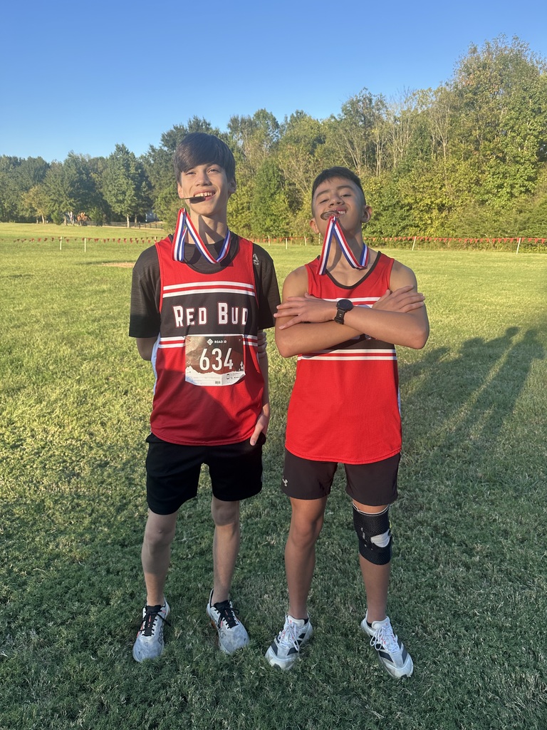 Two boys biting on their medals.