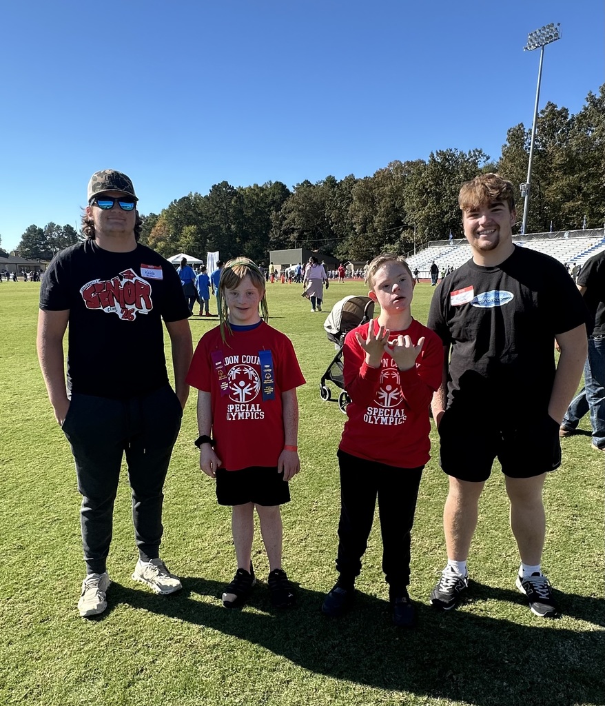 Two young boys standing with two high school boys.