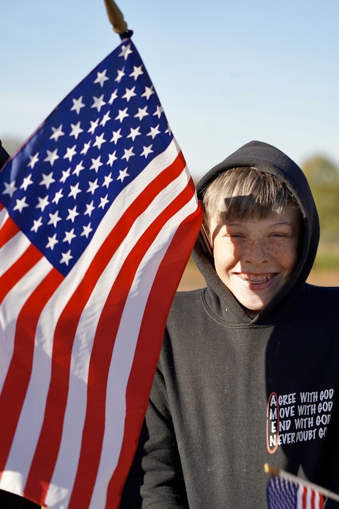 A patriotic picture sowing a boy holding an american flag.