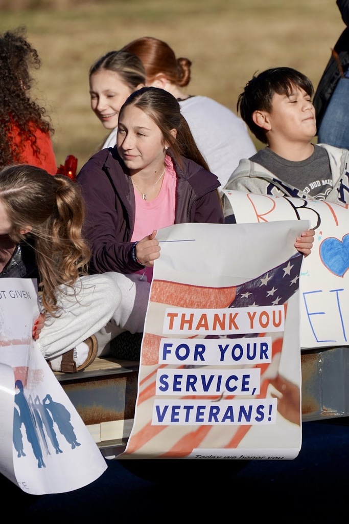 Students holding a sign that says, "Thank you for your service, veterans!"