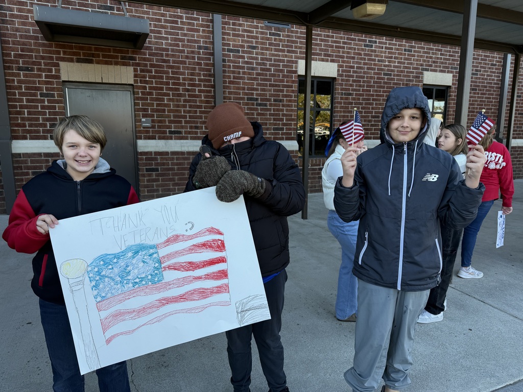 Three boys standing with a flag poster.