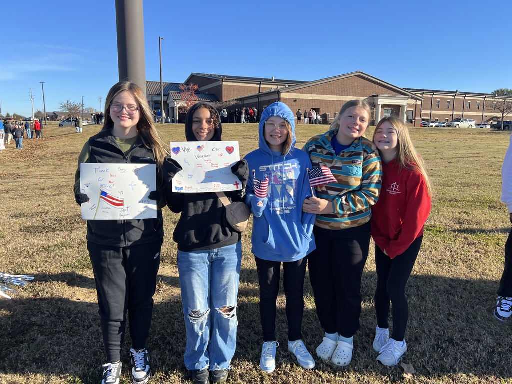 A group of 4 girls holding signs in honor of veterans.