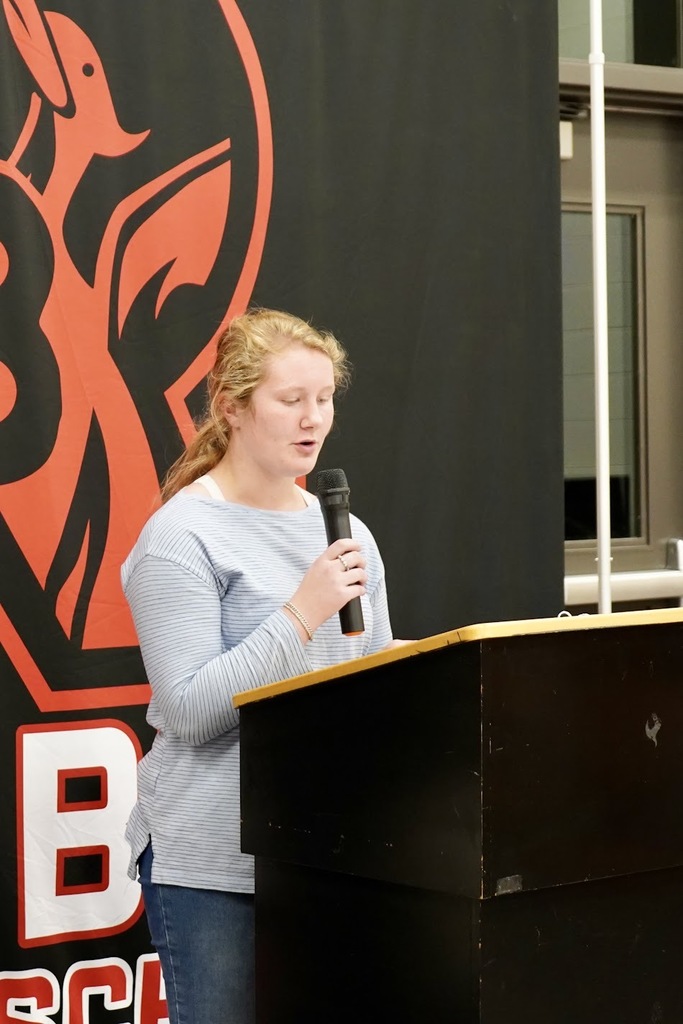 A girl standing behind a podium reading her story.