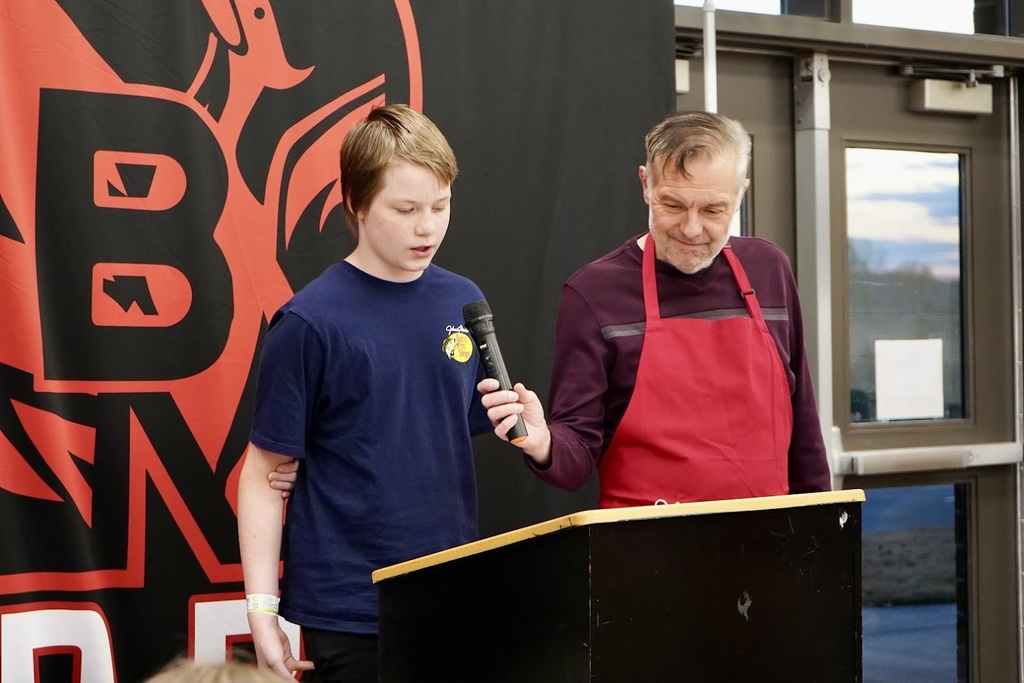 A boy standing behind a podium reading his original story.