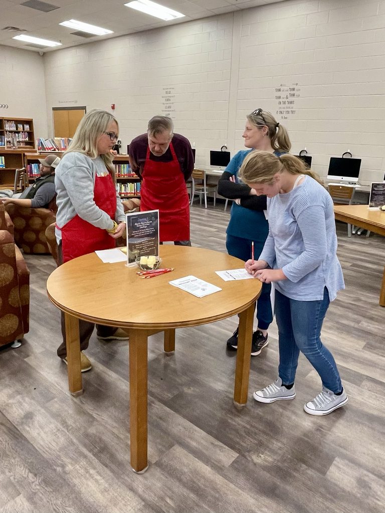 Students and teachers standing around a table.