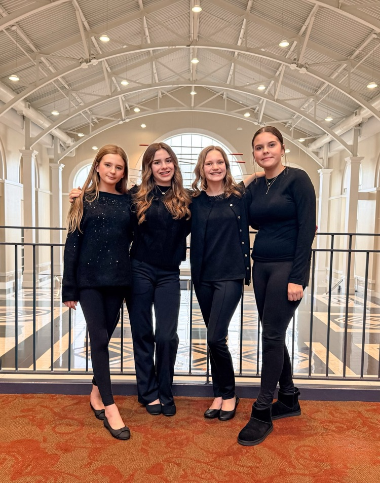 4 girls standing wearing black pants and black shirts  