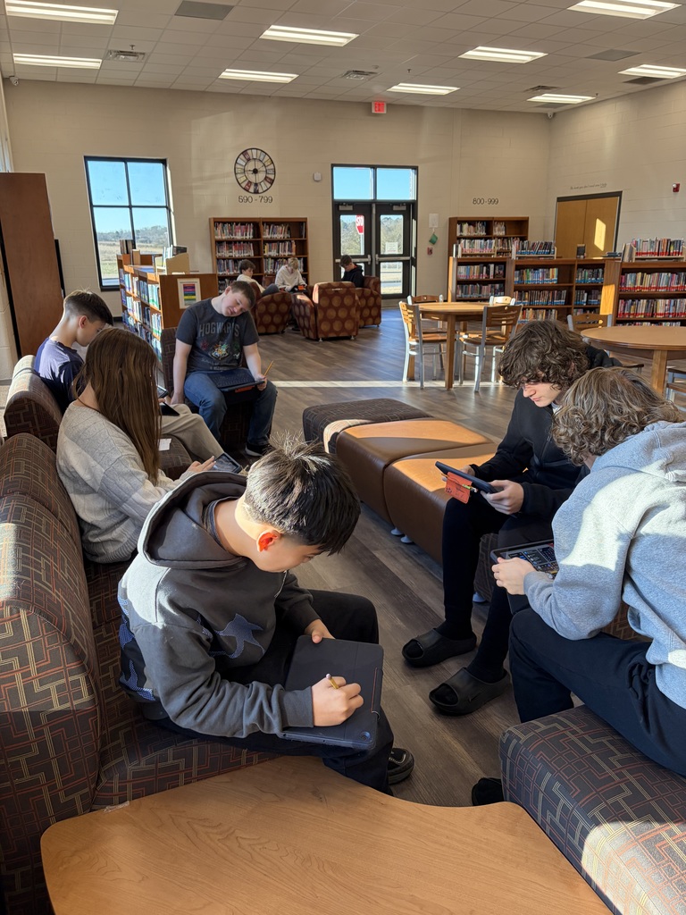 Several students sitting in a library writing poetry.