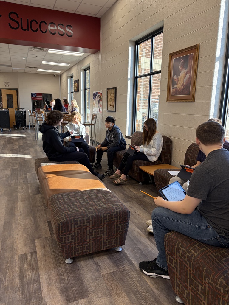 Several students sitting on a sofa while writing poetry.