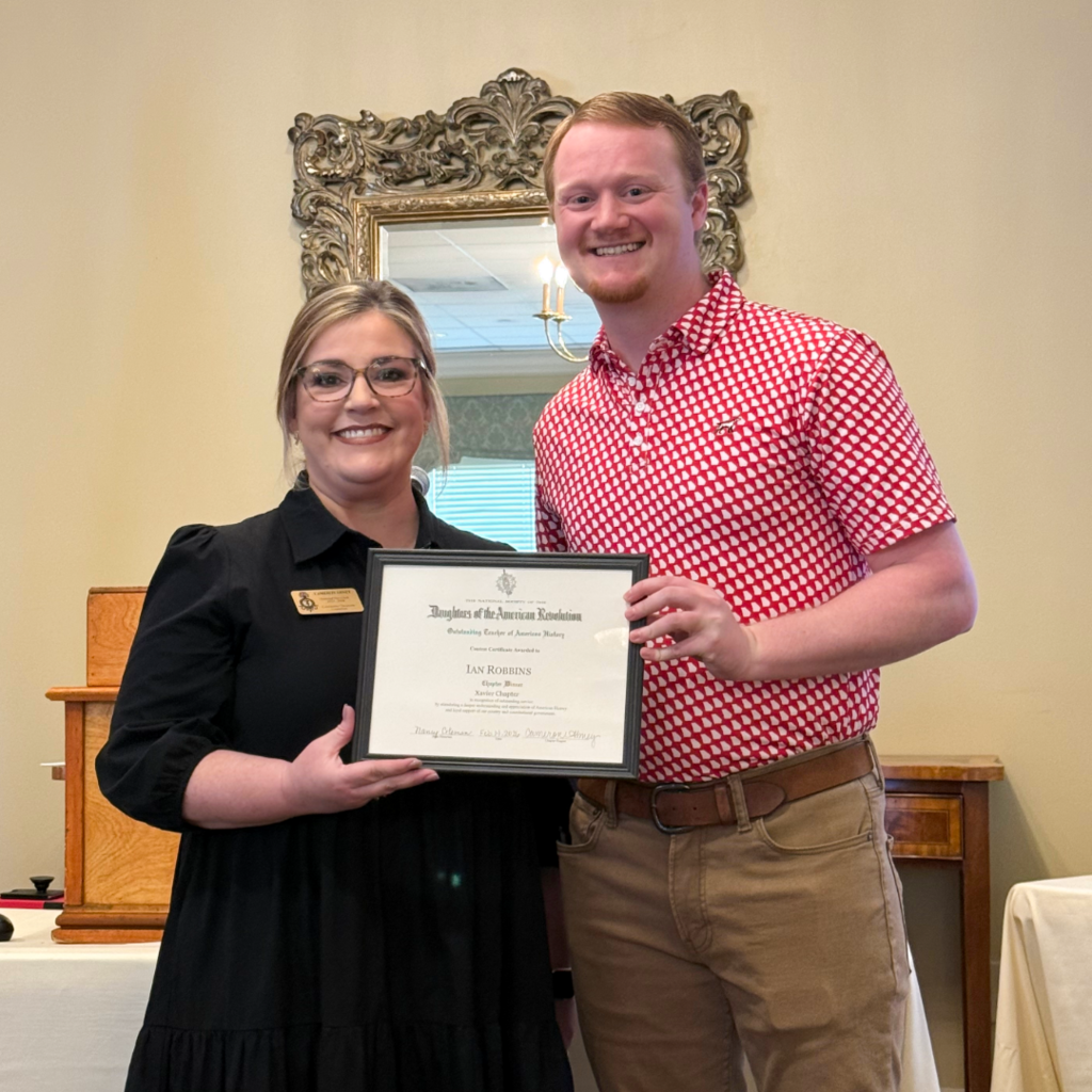 Teacher Ian Robbins being presented a certificate by a Daughters of the American Revolution member.