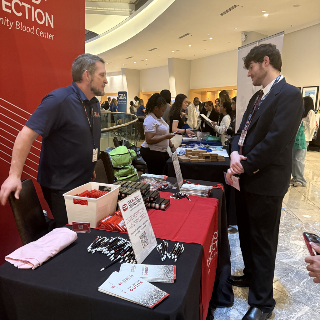 HOSA student receiving information from vendor at conference exhibit. 