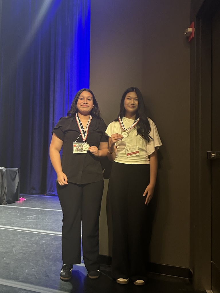 Two girls standing with their 3rd place medals around their necks.