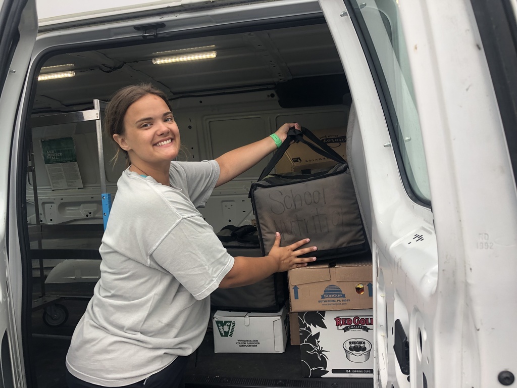 A Summer Feeding Program worker loading boxes and coolers into a delivery van.