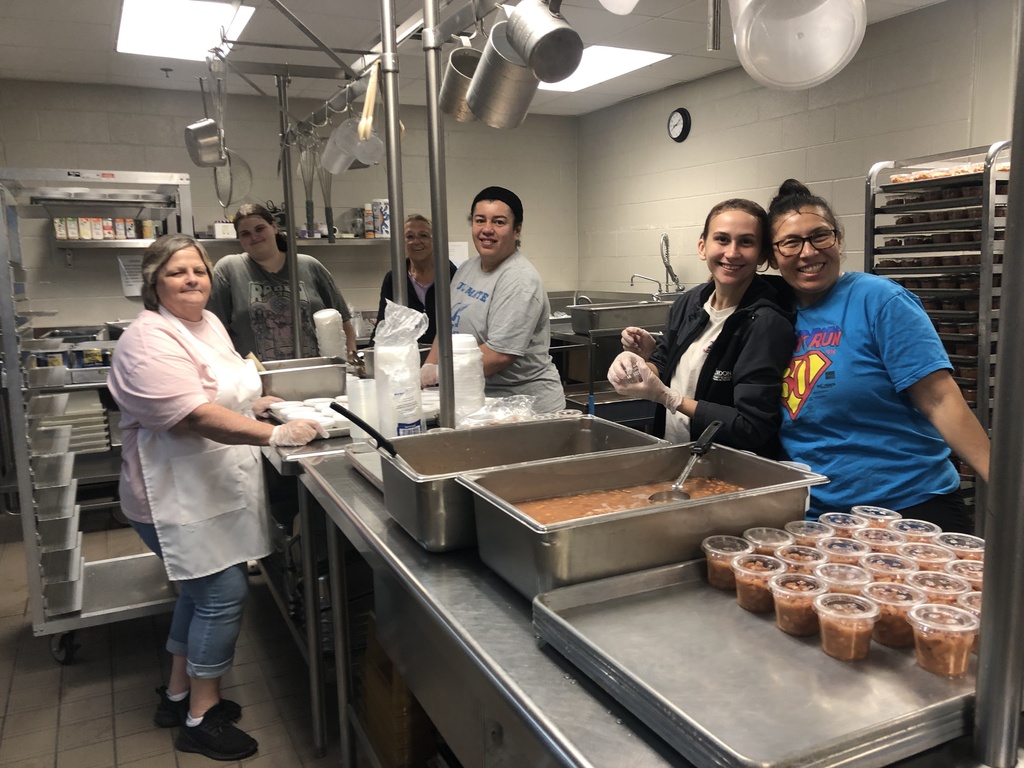 A group of cafeteria workers at a prep table in their kitchen.