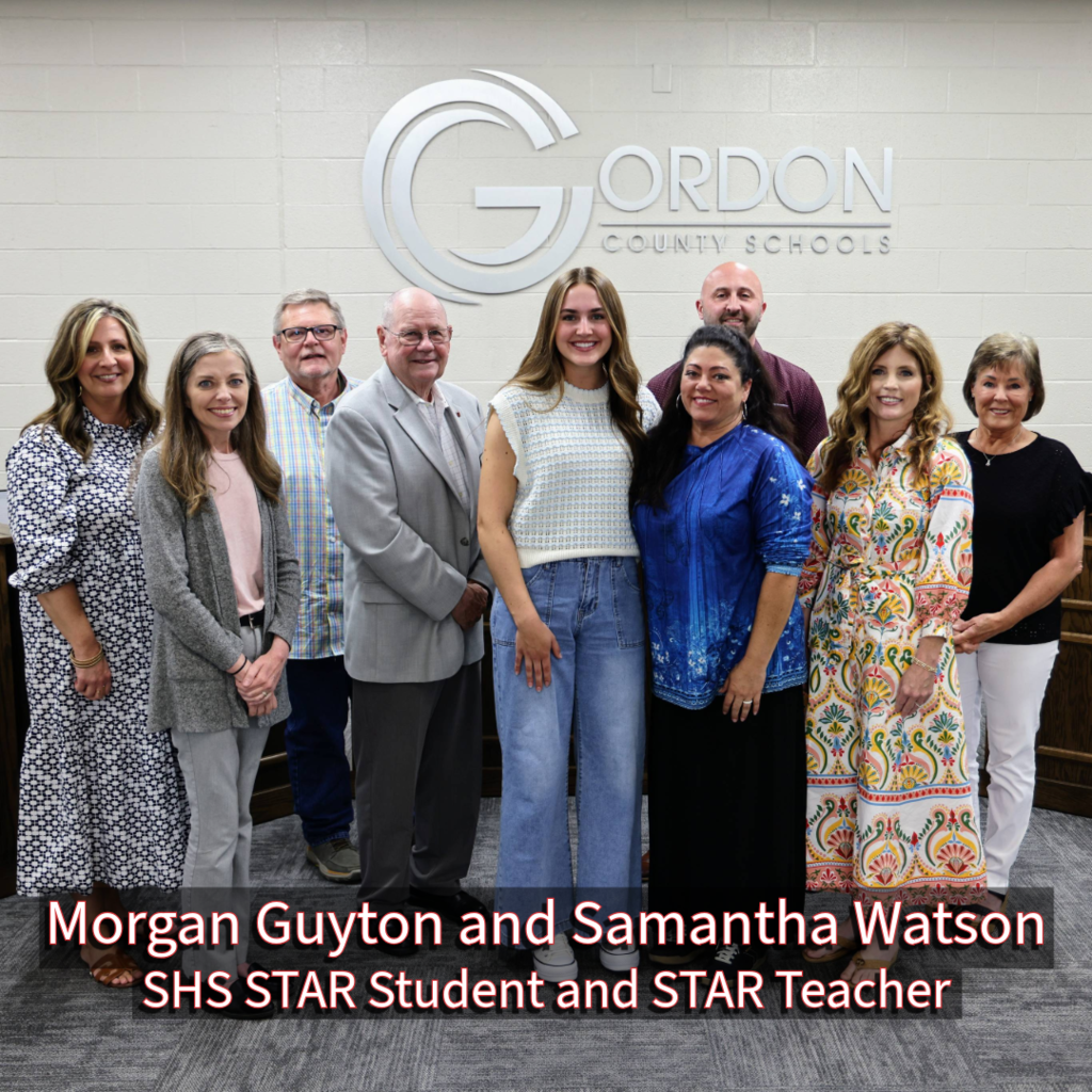 SHS STAR Student and STAR Teacher Morgan Guyton and Samantha Watson with GCS Board of Education members in front of a Gordon County Schools logo
