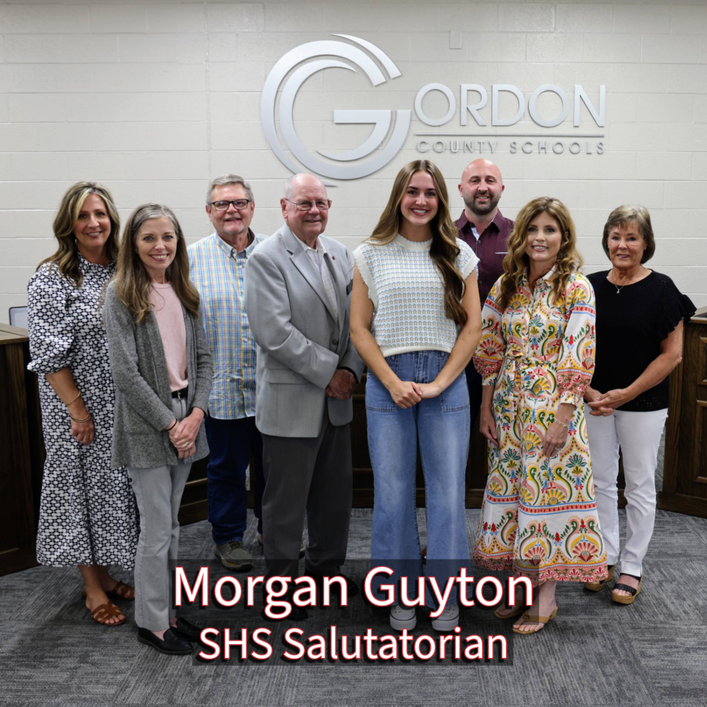 SHS Salutatorian Morgan Guyton with GCS Board of Education members in front of a Gordon County Schools logo