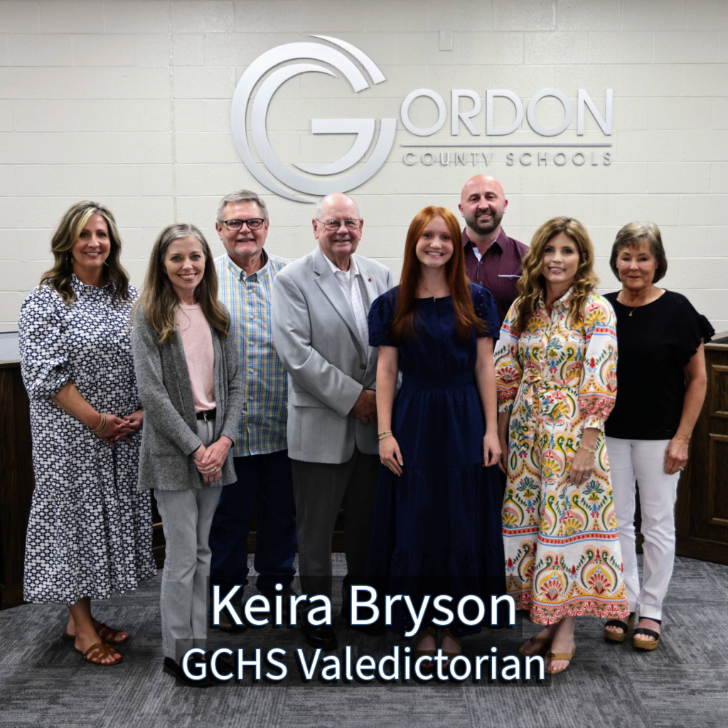 GCHS Valedictorian Keira Bryson with GCS Board of Education members in front of a Gordon County Schools logo