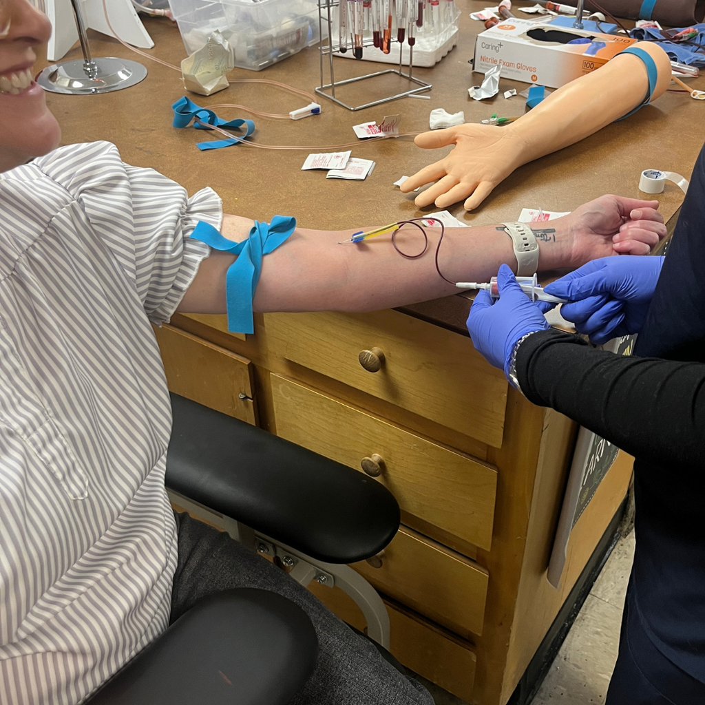 Allied Health student practicing venipuncture & capillary sticks with Mrs. Daina Patterson - licensed phlebotomist and GC staff member