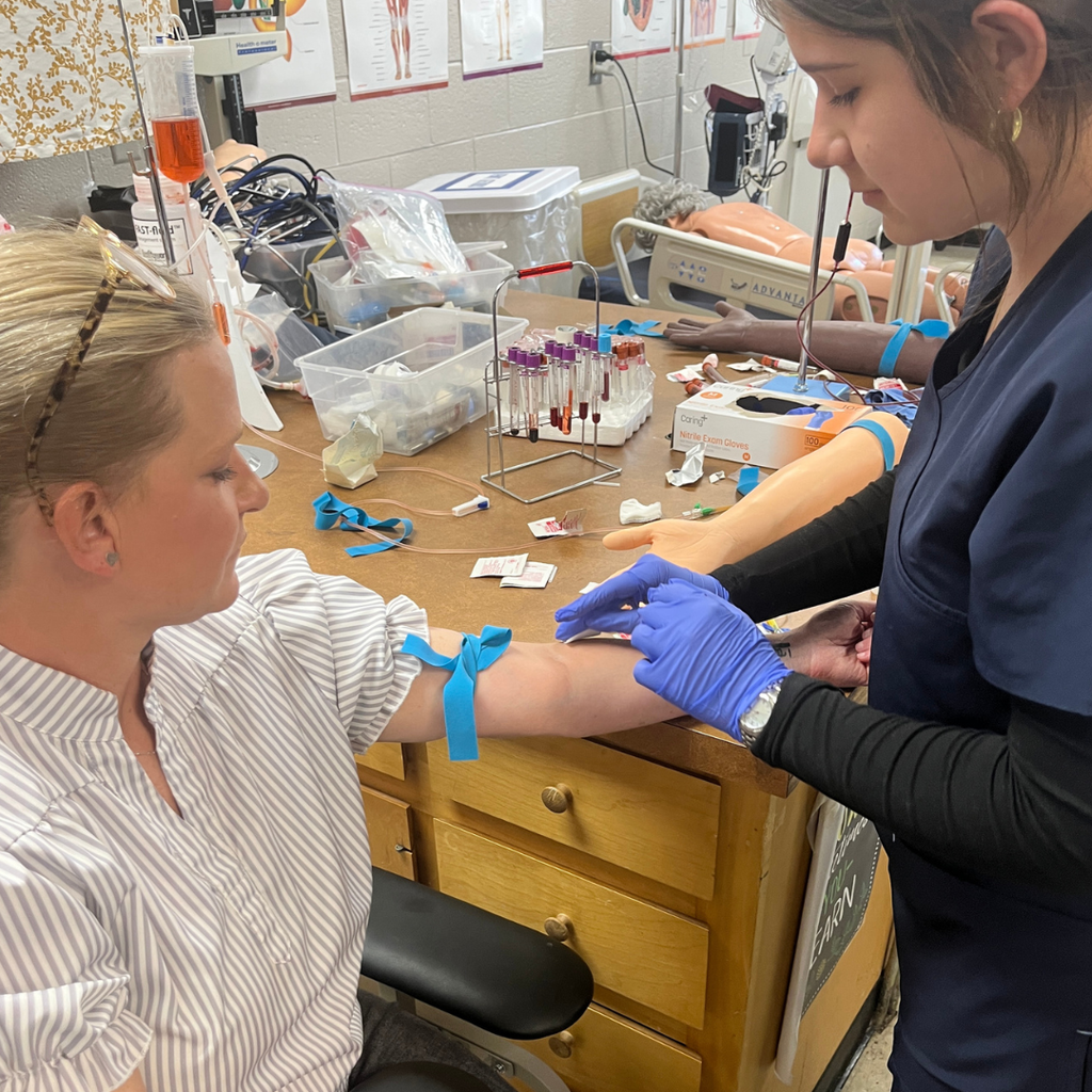 Allied Health student practicing venipuncture & capillary sticks with Mrs. Daina Patterson - licensed phlebotomist and GC staff member