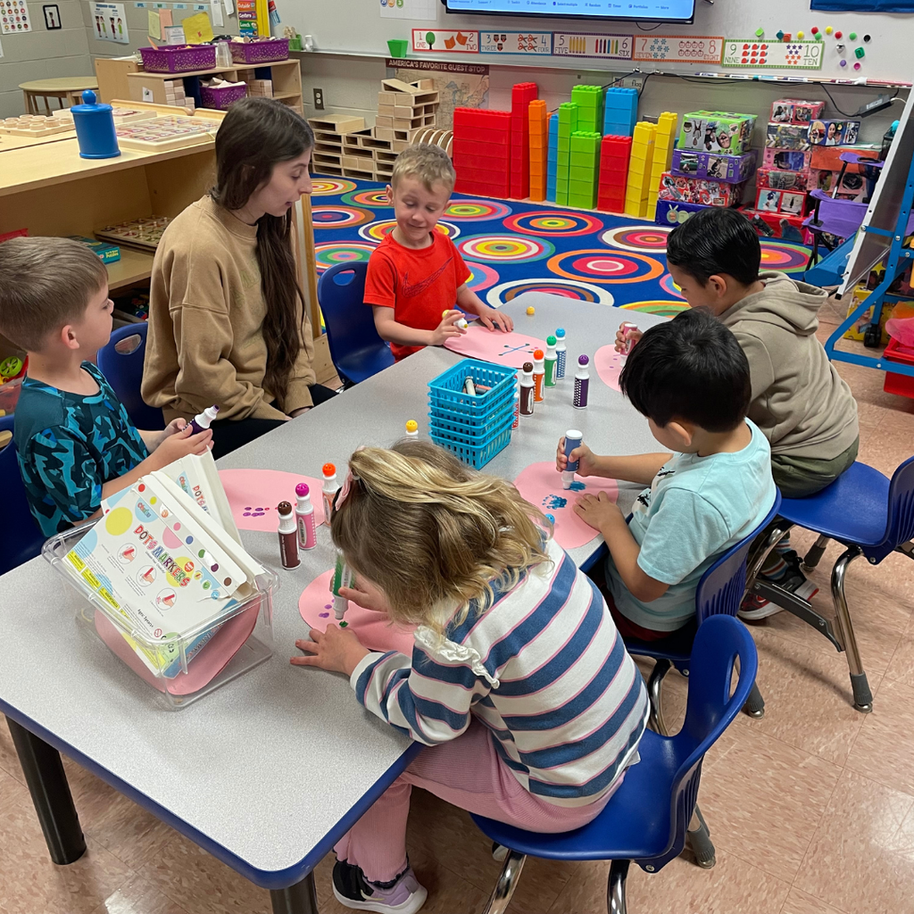 Pic of a GCHS Teaching as a Profession student in elementary classroom environment helping a small group of students