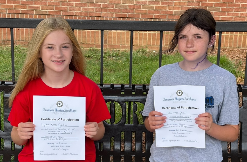 Lydia and Bella showing their certificates for honorable mention of their essay writing.