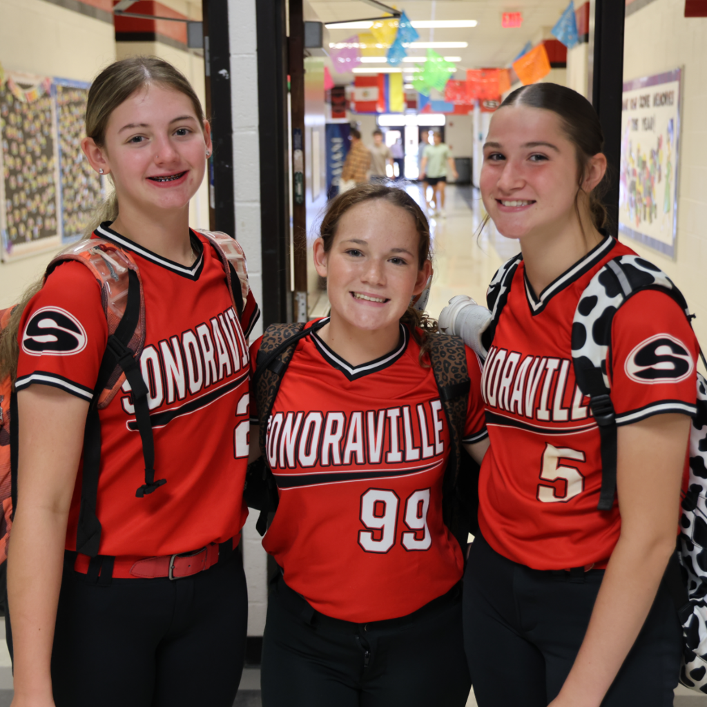 Softball players smiling in the hallway