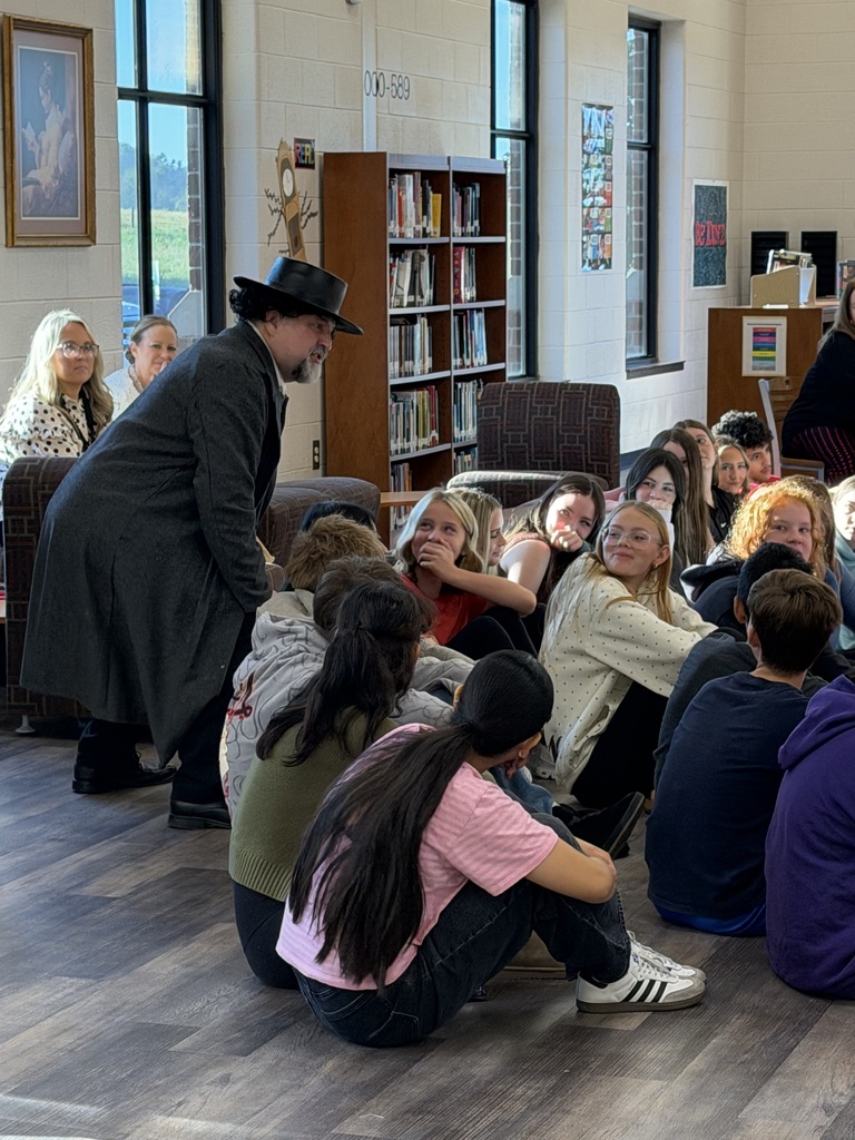 A man posing as Edgar Allen Poe, talks up close and personal with a group of students.