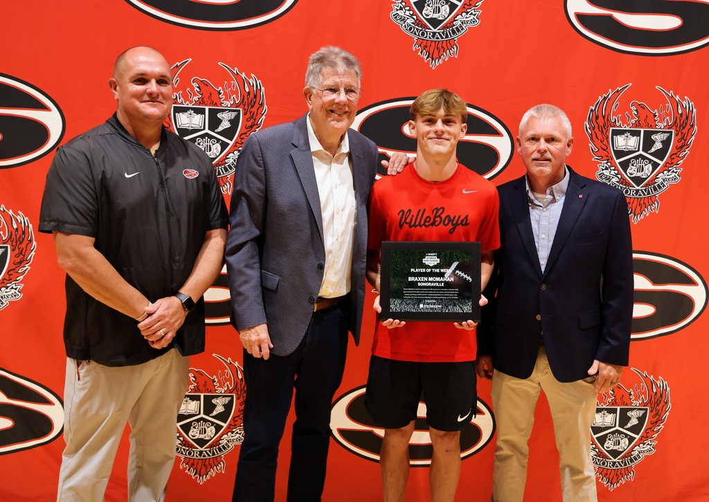 Ceremony honoring Braxen for winning state football player of the week. Posing with AJC and coach