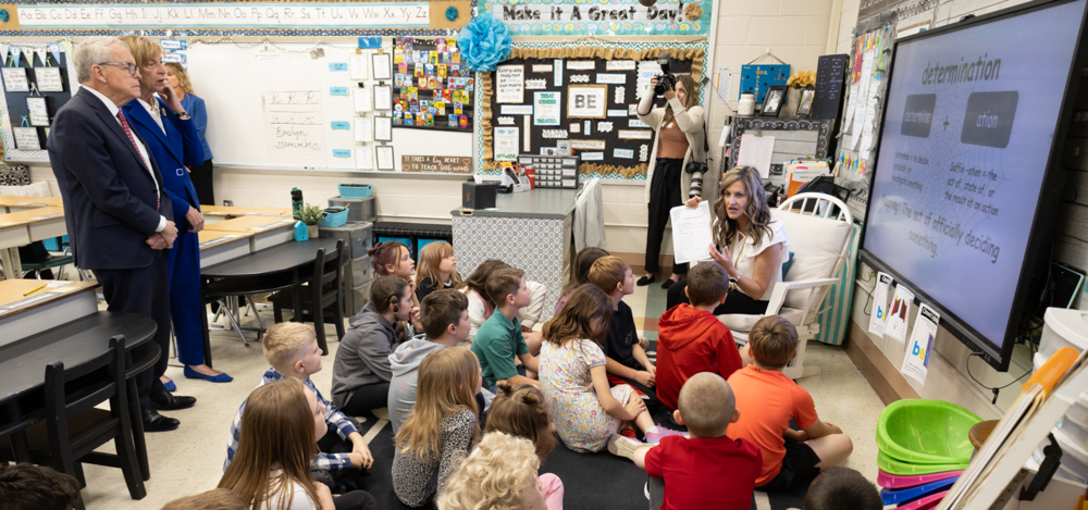 Photo of two adults listening to a reading lesson at an elementary school