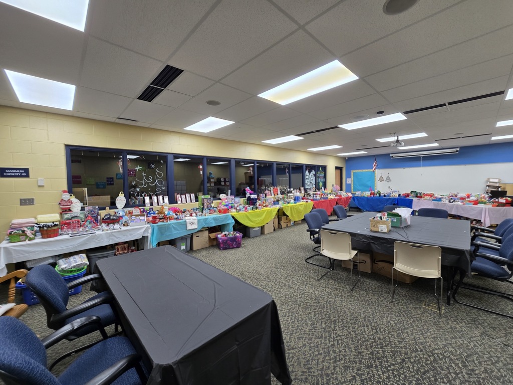 Room with tables set up with different colored table cloths and gift shop items.
