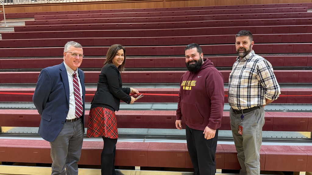 Staff celebrating the new bleachers by ribbon cutting