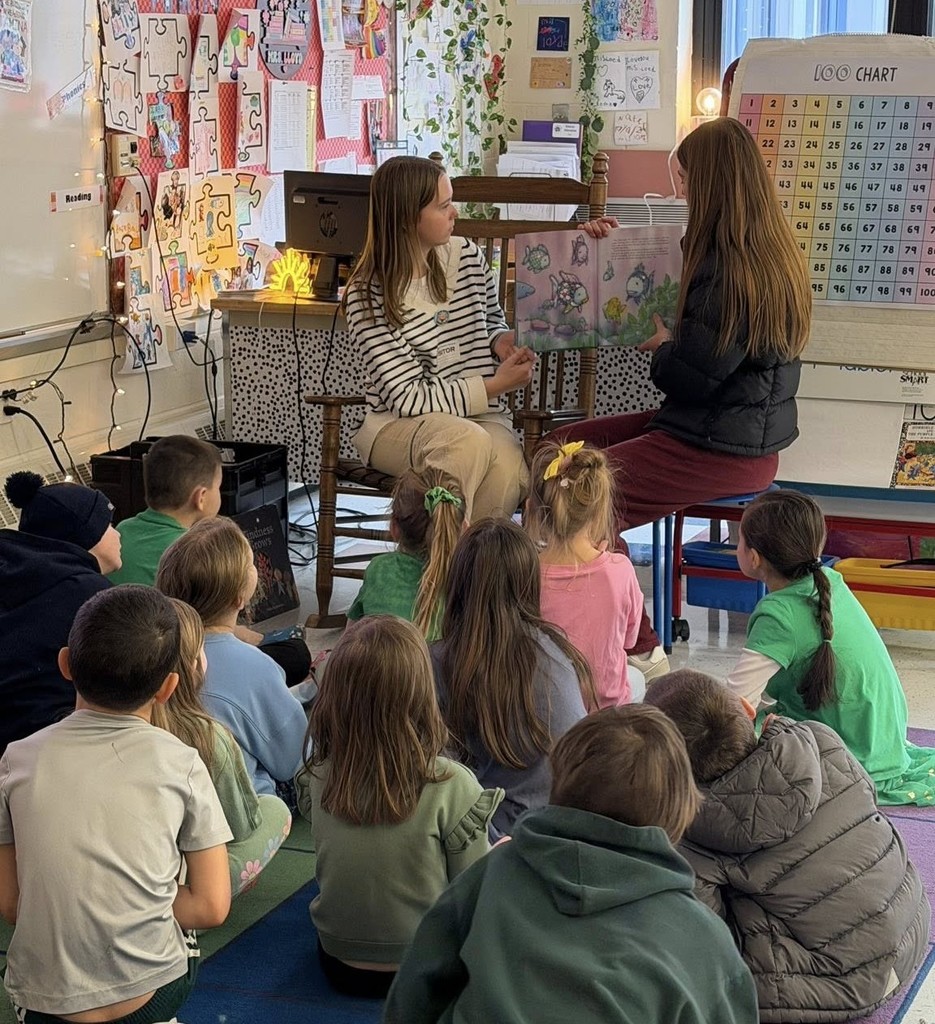 Two students are reading to an elementary class