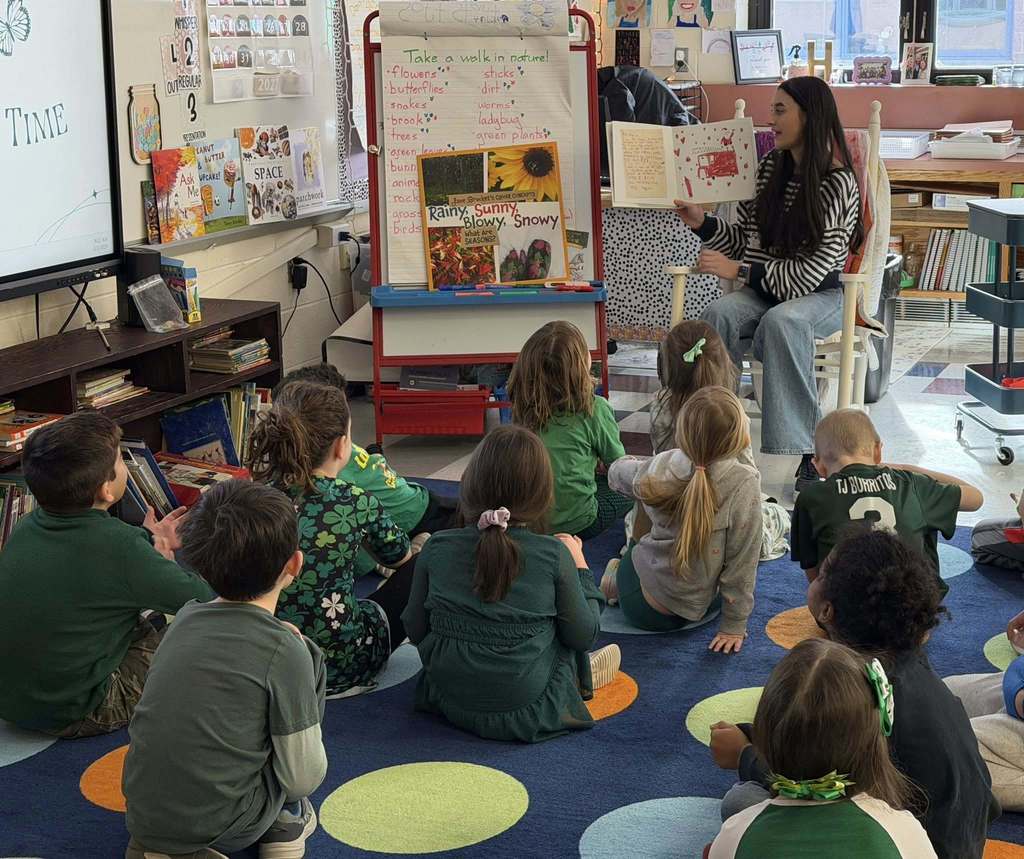 A student is reading a book to a class at Kelly Lane School
