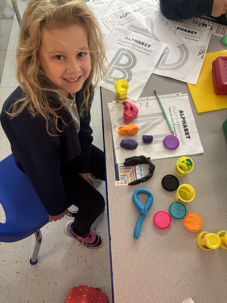 Girl creating playdough letters.