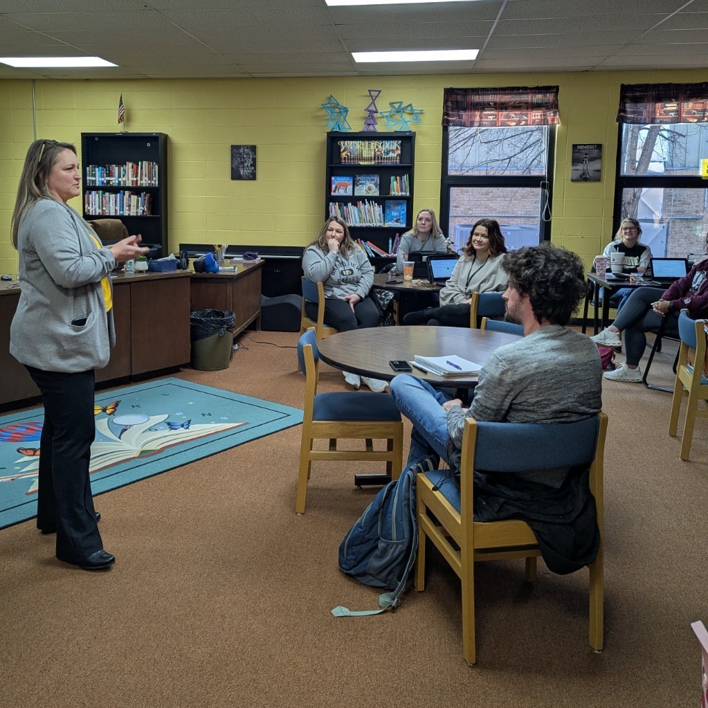A woman speaking to teachers in a school library