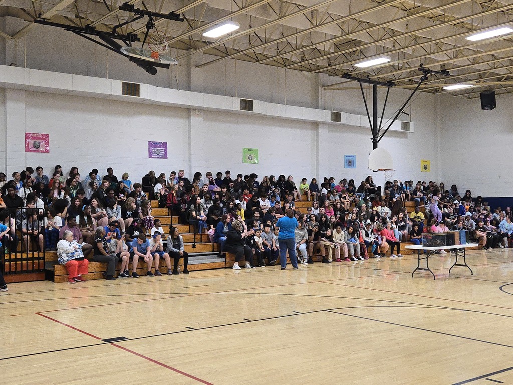 Volunteer from rescue facility  walking in front of students at an assembly