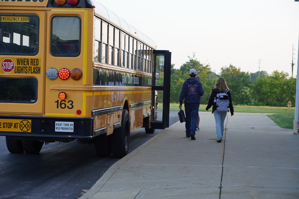 Teenagers walking toward a school bus