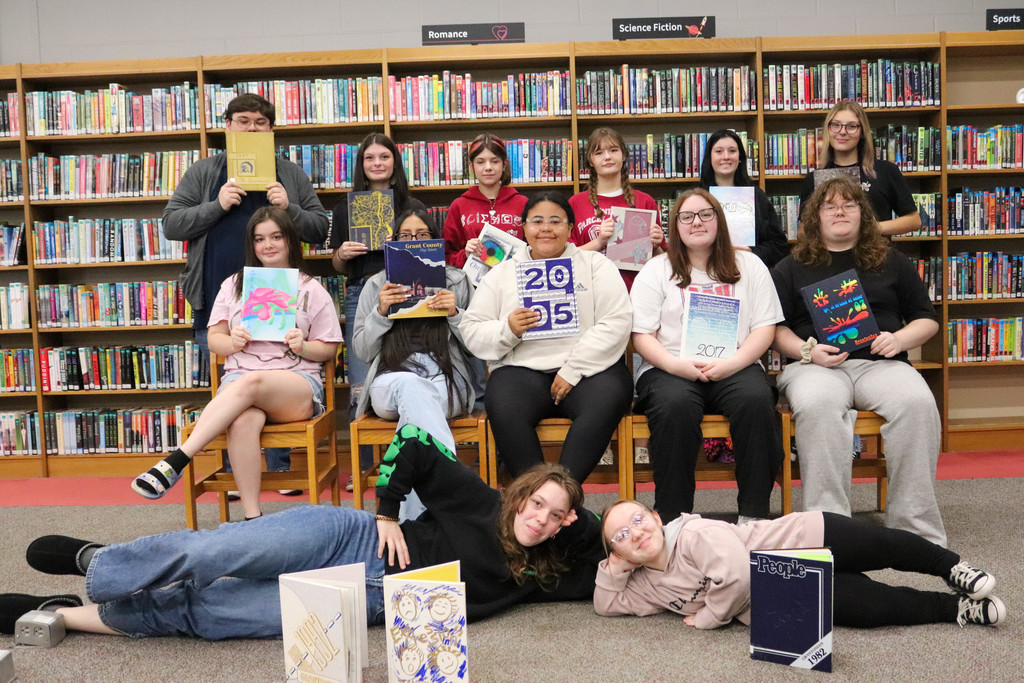 Students holding yearbooks in library