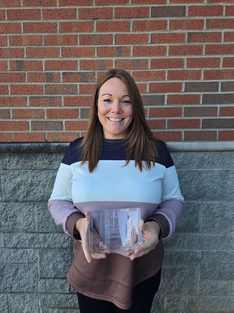 Woman standing in front of bricks holding an award