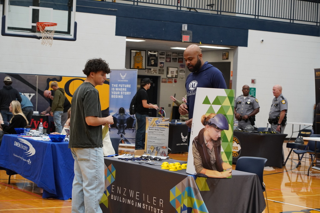 Boy in grey shirt talking to man in blue shirt