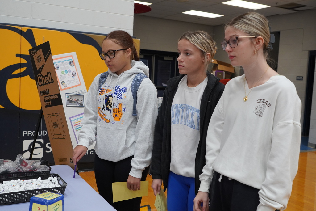 three girls in white hoodies listening