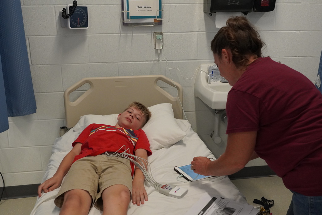 boy on hospital bed, woman in maroon