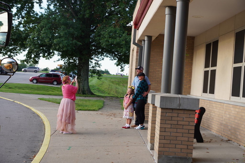 Student posing with parents and teacher taking a photo