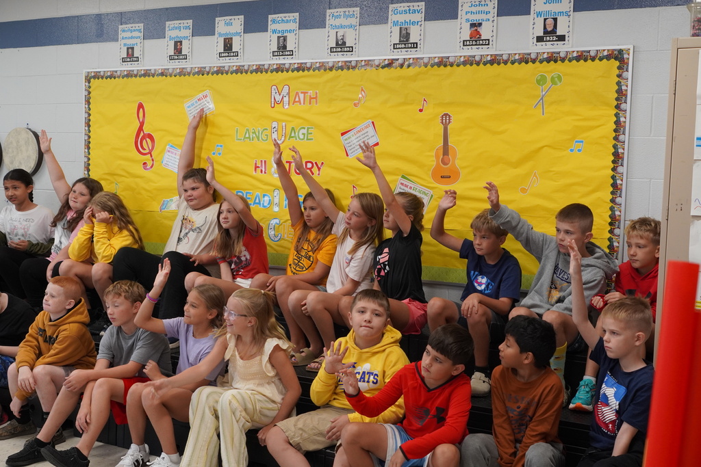 Classroom of children raising their hands