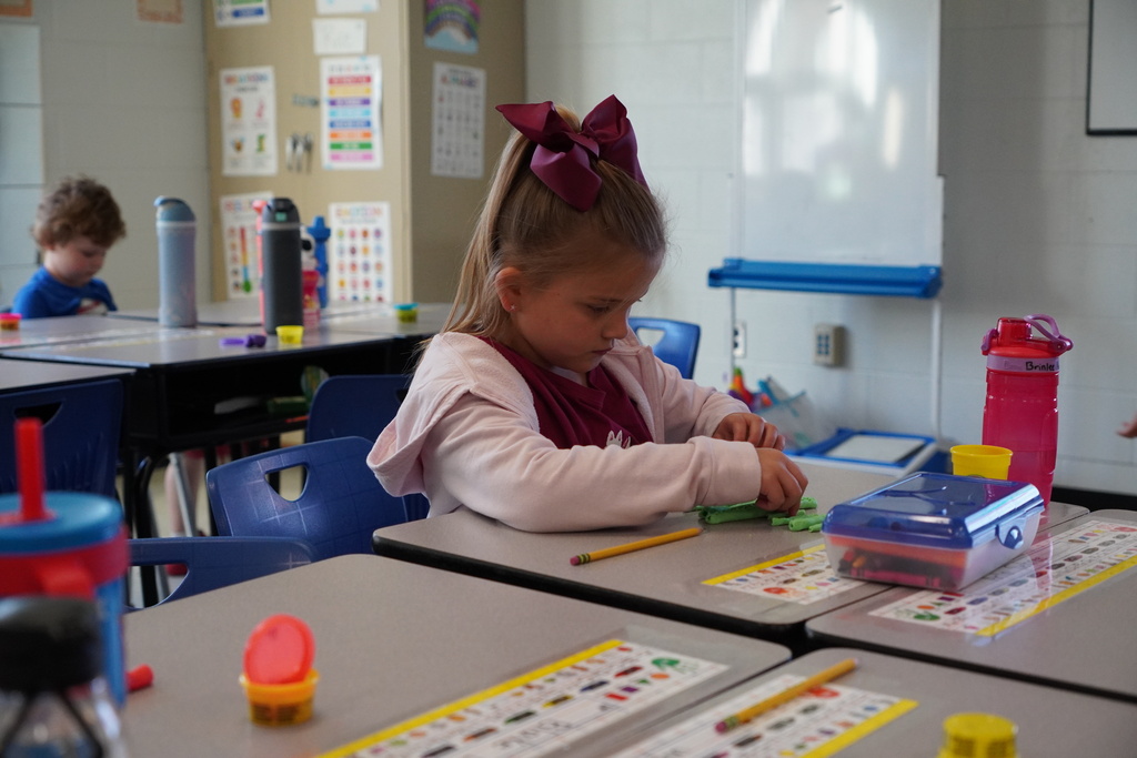 Young girl with maroon bow working at her student desk