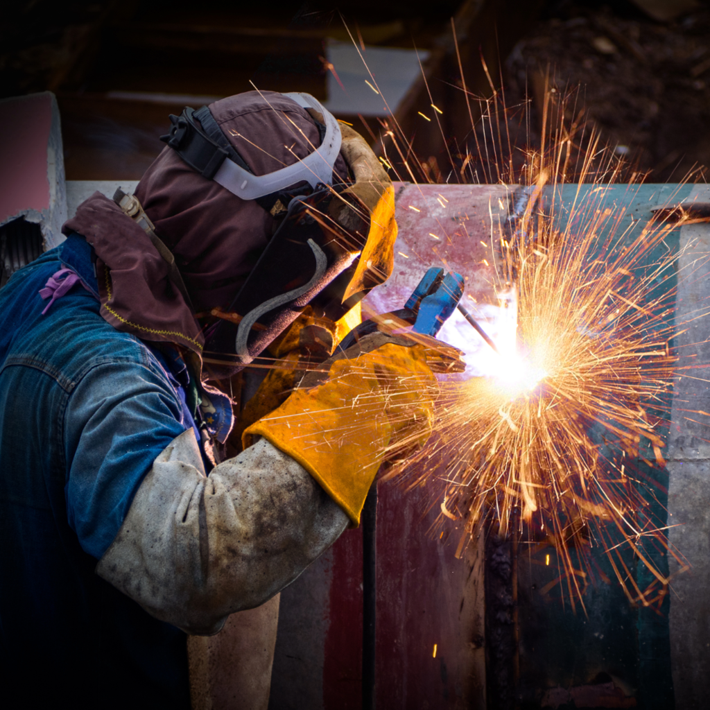 welder with red sparks, gloves, and welding helmet
